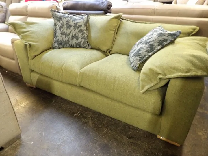 Green fabric sofa with scatter cushions on display