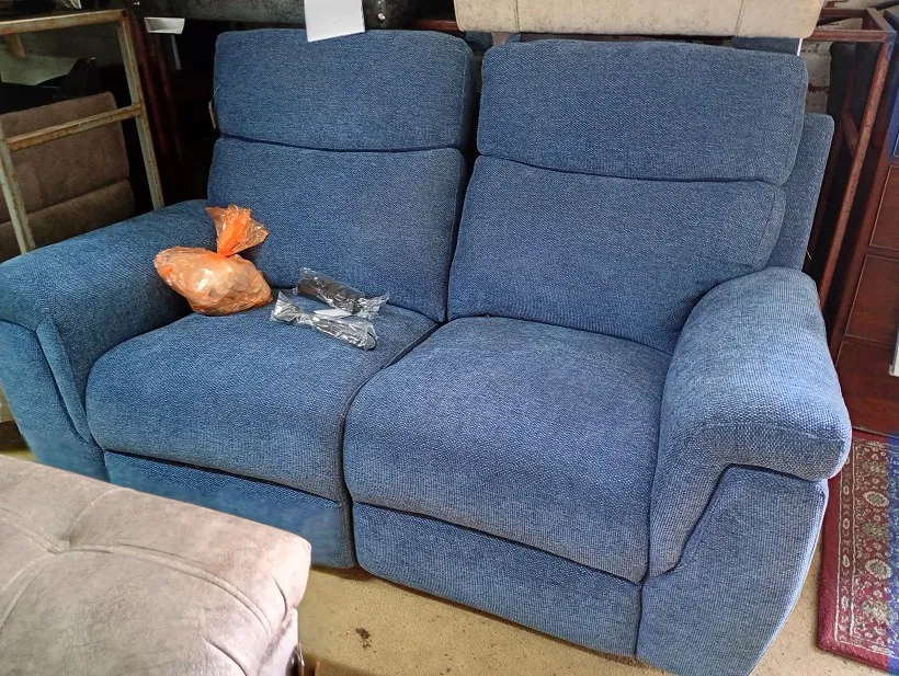 Blue textured weave fabric 2 seater sofa with reclining mechanism and a bagged accessory on the seat