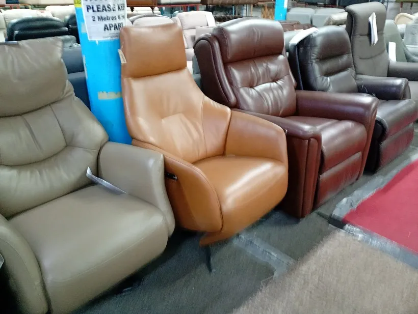 Tan leather recliner armchair with high back and wing back, shown with other leather recliners