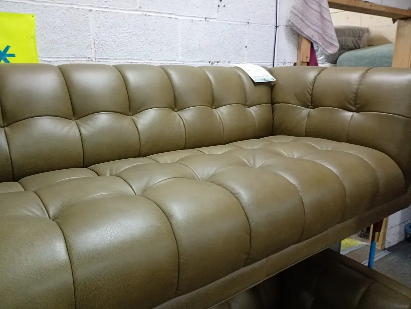 Olive green leather deep-buttoned sofa with tufted back and seat, close-up of the upholstery detail