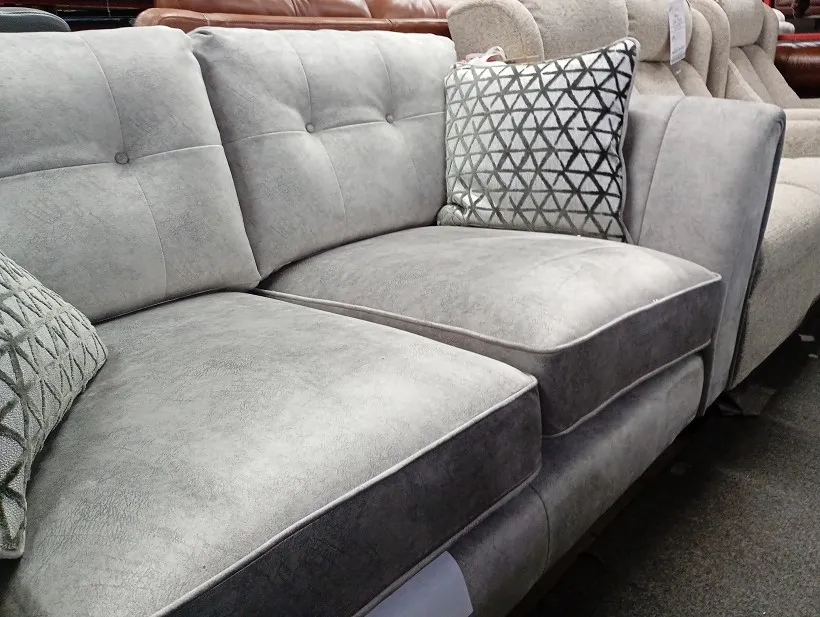 Light grey fabric corner sofa with buttoned back cushions and geometric scatter cushion